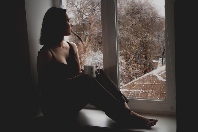 Persona in silenzio vicino a una finestra, in un momento difficile